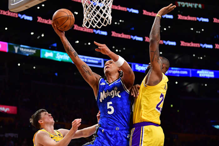 Orlando Magic forward Paolo Banchero (5) muscles in a layup against Los Angeles Lakers forward LeBron James (23)